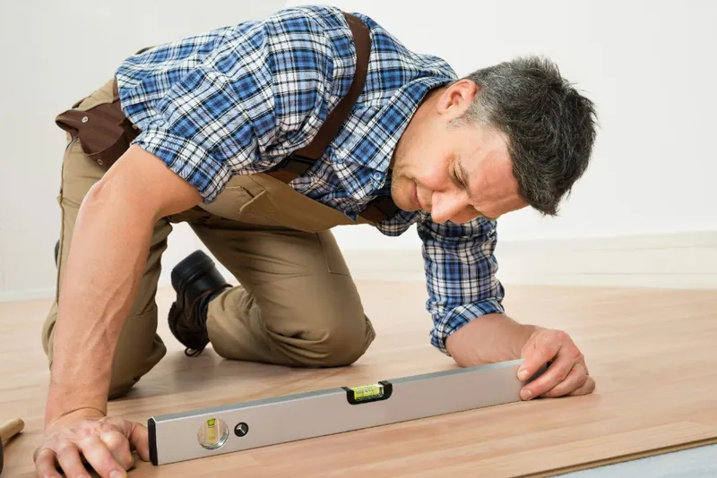 Carpenter installing a brand-new laminated wooden floor in a flat