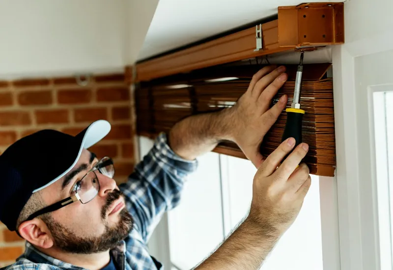 Two handymen mounting fresh window blinds and curtains in an apartment