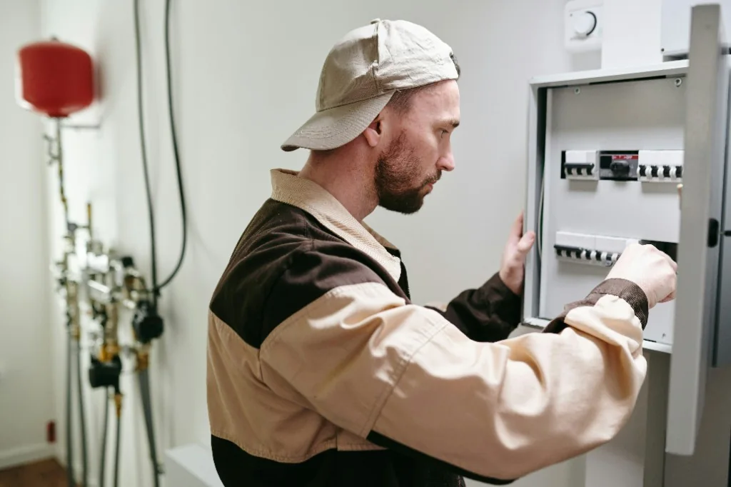 Qualified electrician adjusting a fuse-box dashboard on a wall in an Austrian home