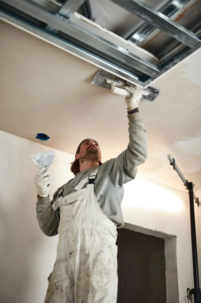 Painter plastering and finishing a fresh ceiling inside an Austrian home