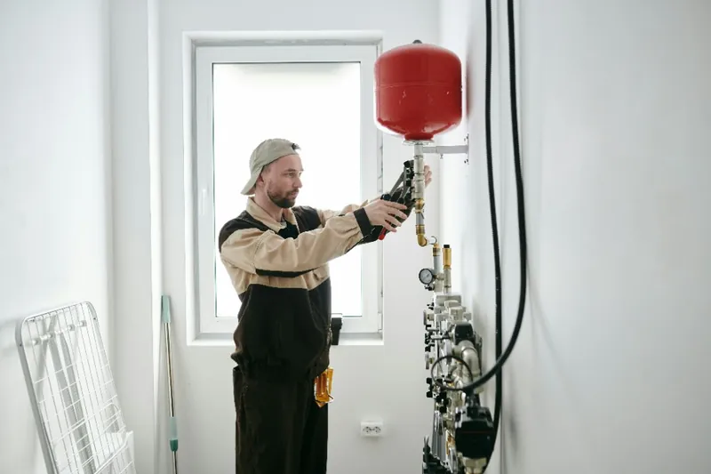 Plumber installing a modern toilet and heating tank in a bathroom