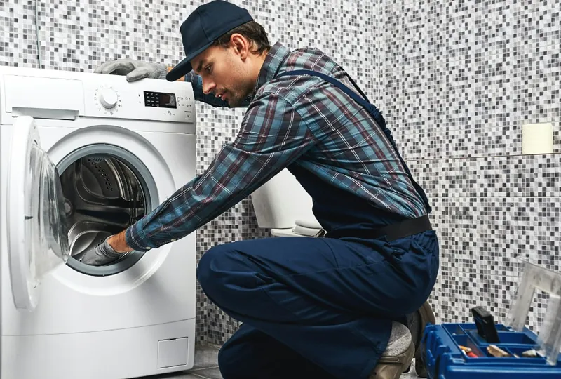 Plumber repairing a leaking washing machine in a laundry room